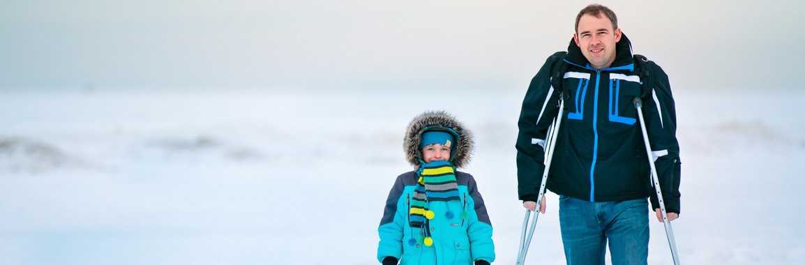 Father using crutches with child. Going for a walk outside.