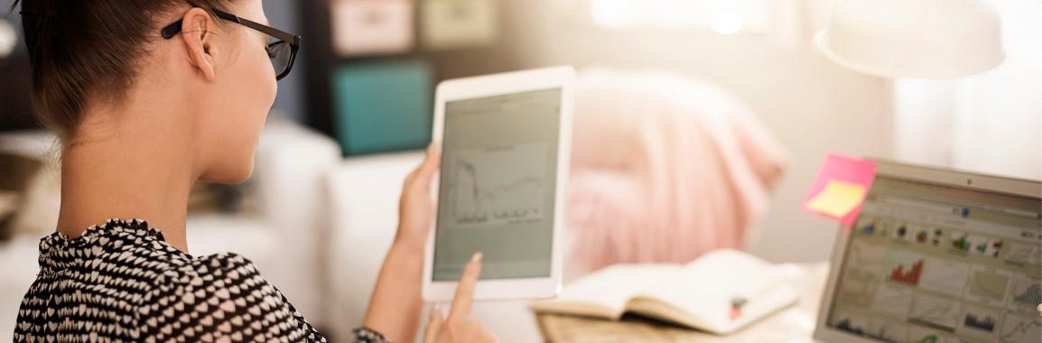 Woman using financial tools on a tablet and laptop.