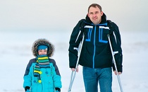 Father on crutches who is walking with his son.